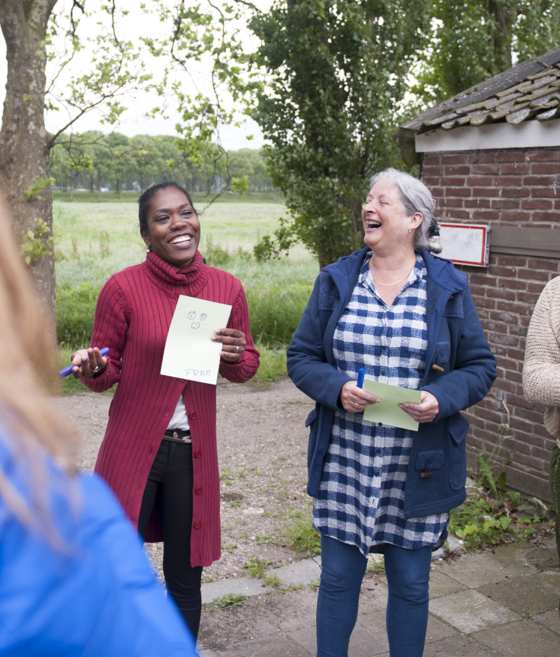 Black woman speaking from a piece of paper in a circle with other women surrounding her outside.