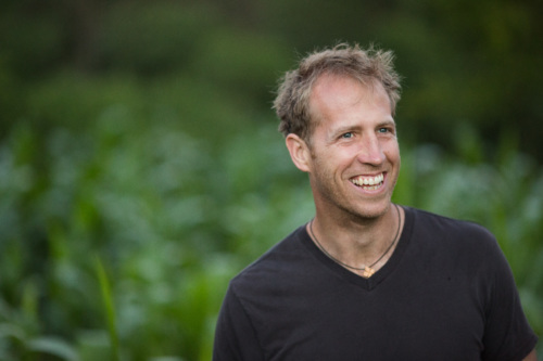 Jake Harriman, a tall white man with blonde hair, smiling in front of a grassy field