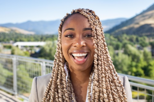 headshot of Imarii Poindexter, a Black woman wearing a tan suit, with the mountains in the background