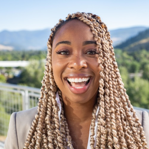 headshot of Imarii Poindexter, a Black woman wearing a tan suit, with the mountains in the background