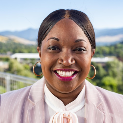 headshot of Mary Tobin, a Black woman, wearing a light pink jacket and white blouse, with mountains in the background