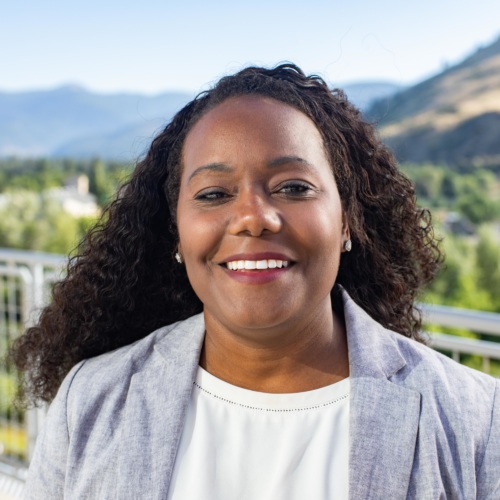 headshot of Terrill McFarland, a Black woman wearing a blue suit, with mountains in the background