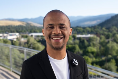 headshot of Archie Nettles, a Black man wearing a black jacket and white shirt, with mountains in the background.