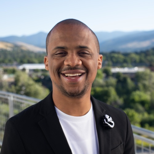 headshot of Archie Nettles, a Black man wearing a black jacket and white shirt, with mountains in the background.