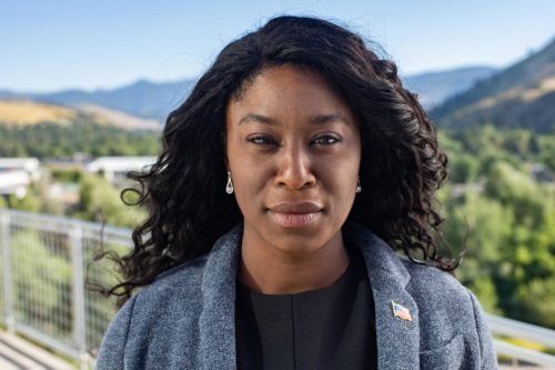 headshot of Charlynda Scales, a Black woman wearing a blue blazer, and mountains in the background