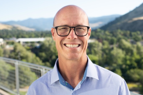 headshot of Keith Galloway, a white bald man with glasses, and mountains in the background