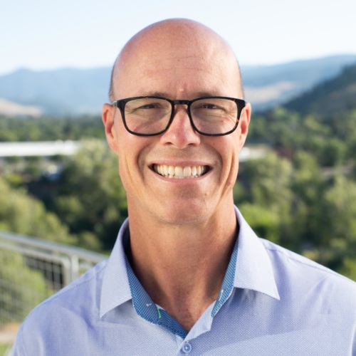 headshot of Keith Galloway, a white bald man with glasses, and mountains in the background