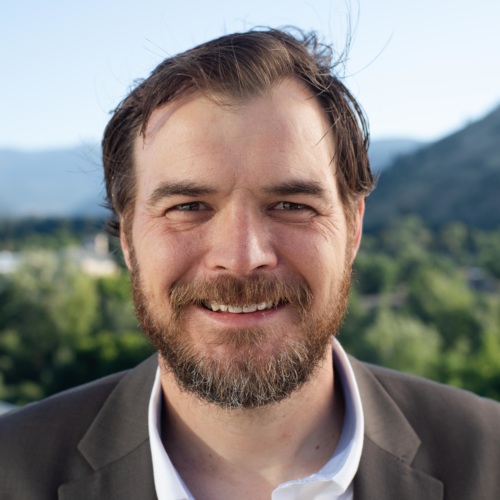headshot of Ryan Woolf with mountains in the background