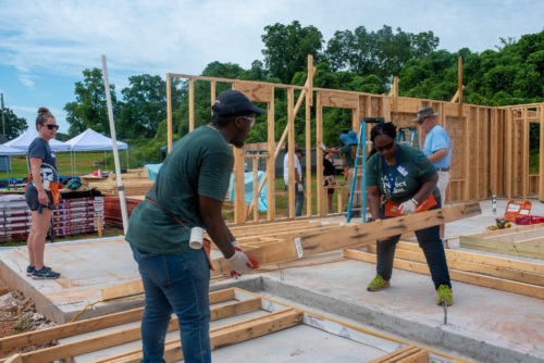 More Perfect Union members lifting wall frames to build a house