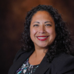 A headshot of Alice Garcia, a hispanic woman wearing a black suit jacket.