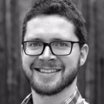 Black and white headshot of Ben Lyon, a white man with a beard and glasses.