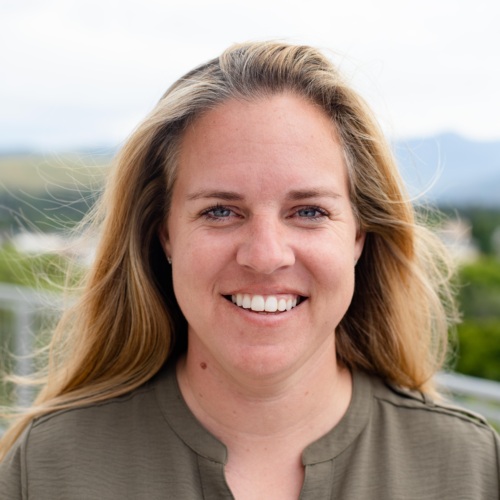 Headshot of Sara Hunold, a white woman with blonde hair standing in front of scenic mountains