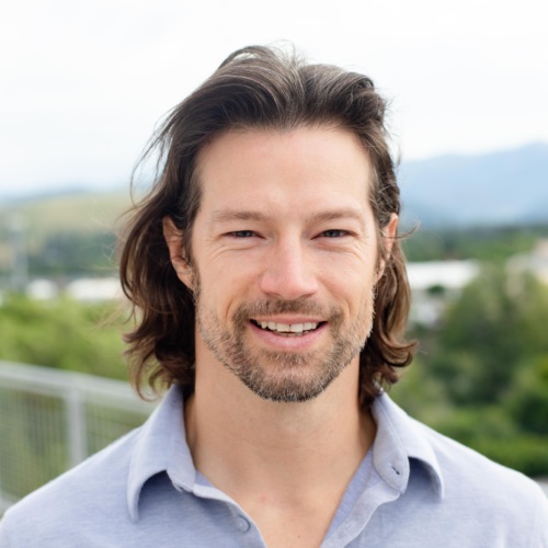 Headshot of Trip O'Connell, a white man with long brown hair in front of scenic mountains