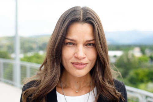 Headshot of Katarina Vargas, a multiracial woman with brown hair standing in front of scenic mountains