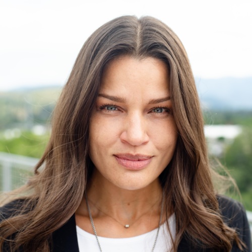 Headshot of Katarina Vargas, a multiracial woman with brown hair standing in front of scenic mountains