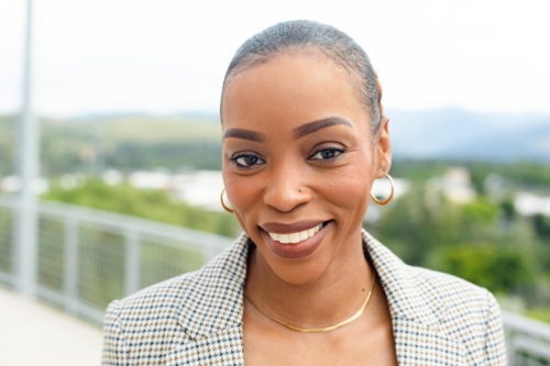 Headshot of Olyvia Troop, a Black woman smiling with scenic mountains in the background