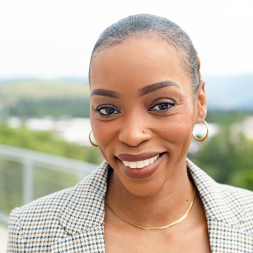 Headshot of Olyvia Troop, a Black woman smiling with scenic mountains in the background