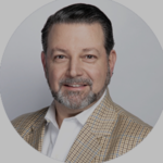 Headshot of Larry Danna, a white man with a grey beard wearing a suit