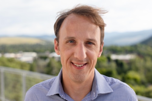 Headshot of Matt Dembowski, a white man wearing a collared shirt standing in front of scenic mountains