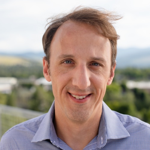 Headshot of Matt Dembowski, a white man wearing a collared shirt standing in front of scenic mountains