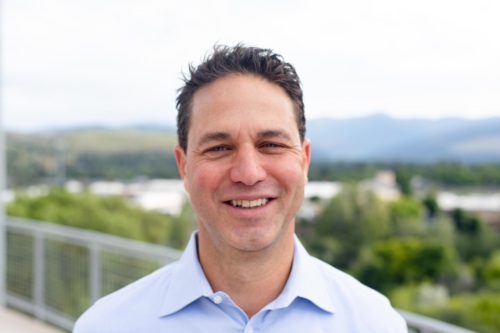 Headshot of Sam LaNasa, a white man standing in front of scenic mountains.