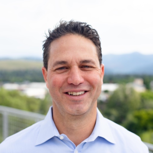 Headshot of Sam LaNasa, a white man standing in front of scenic mountains.