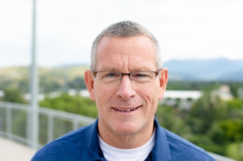 Headshot of Steve Woll, a white man standing in front of scenic mountains