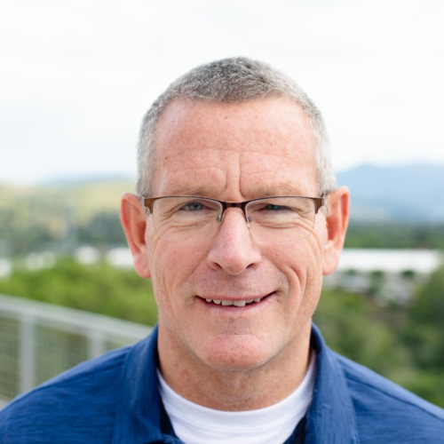 Headshot of Steve Woll, a white man standing in front of scenic mountains