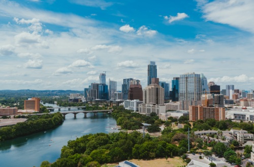 Downtown Austin Texas, with big skyscrapers, a river, and bright green trees.
