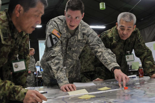 Three men in uniform pointing at a map