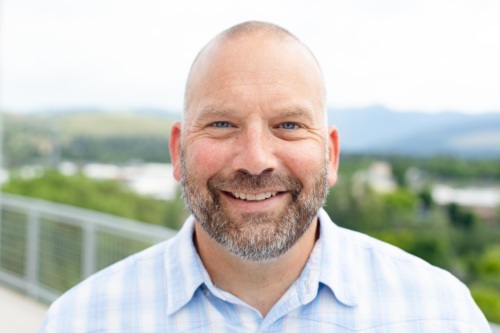 Headshot of Brian Von Herbulis, a bald white man wearing a blue collared shirt