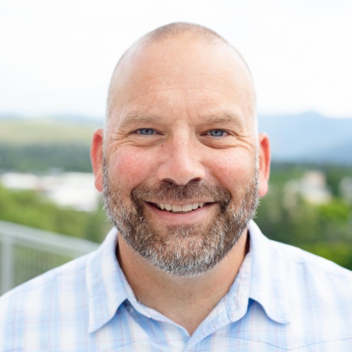 Headshot of Brian Von Herbulis, a bald white man wearing a blue collared shirt
